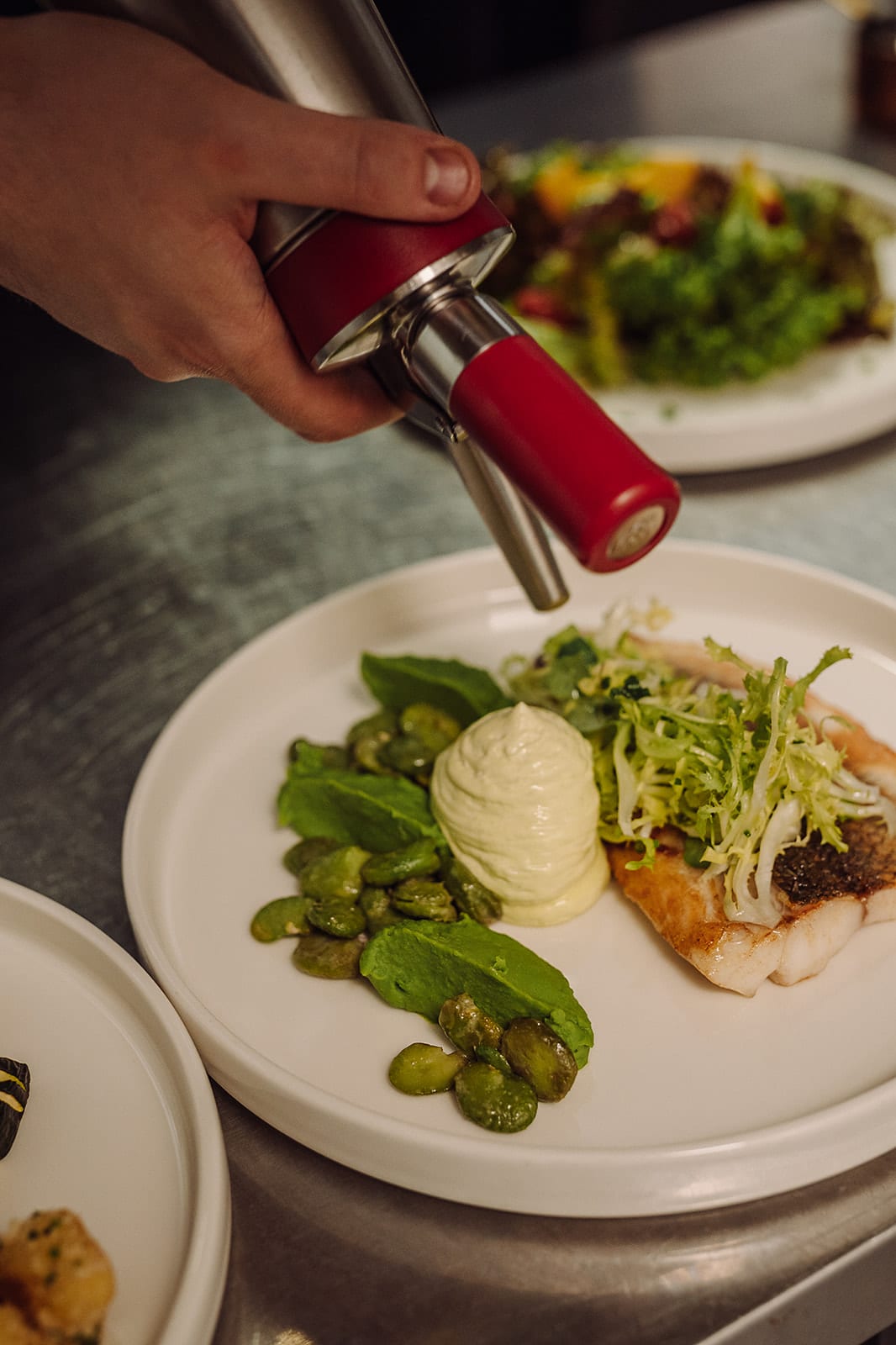 Ein Fischgericht wird in der Küche mit dem Siphon vollendet