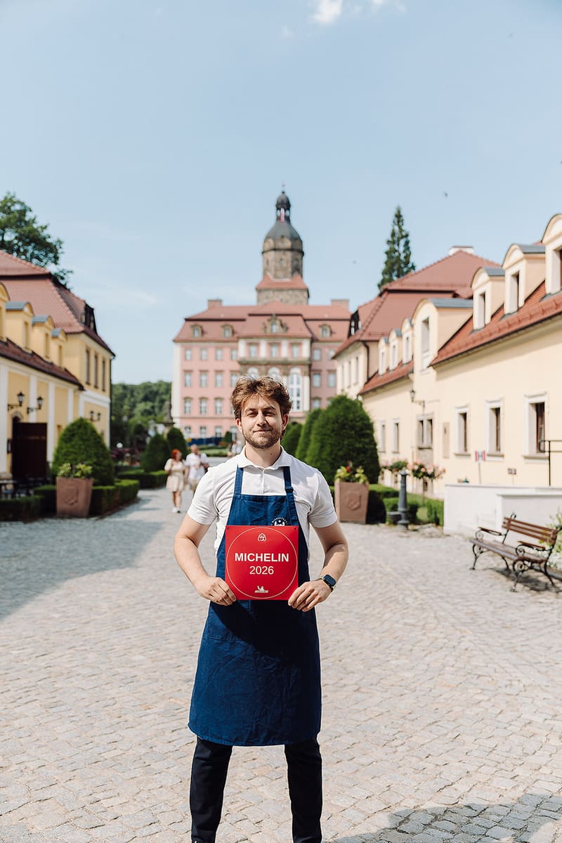 Das Team des Restaurants Biblioteka mit der MICHELIN-Plakette 2026 im Hof von Schloss Książ