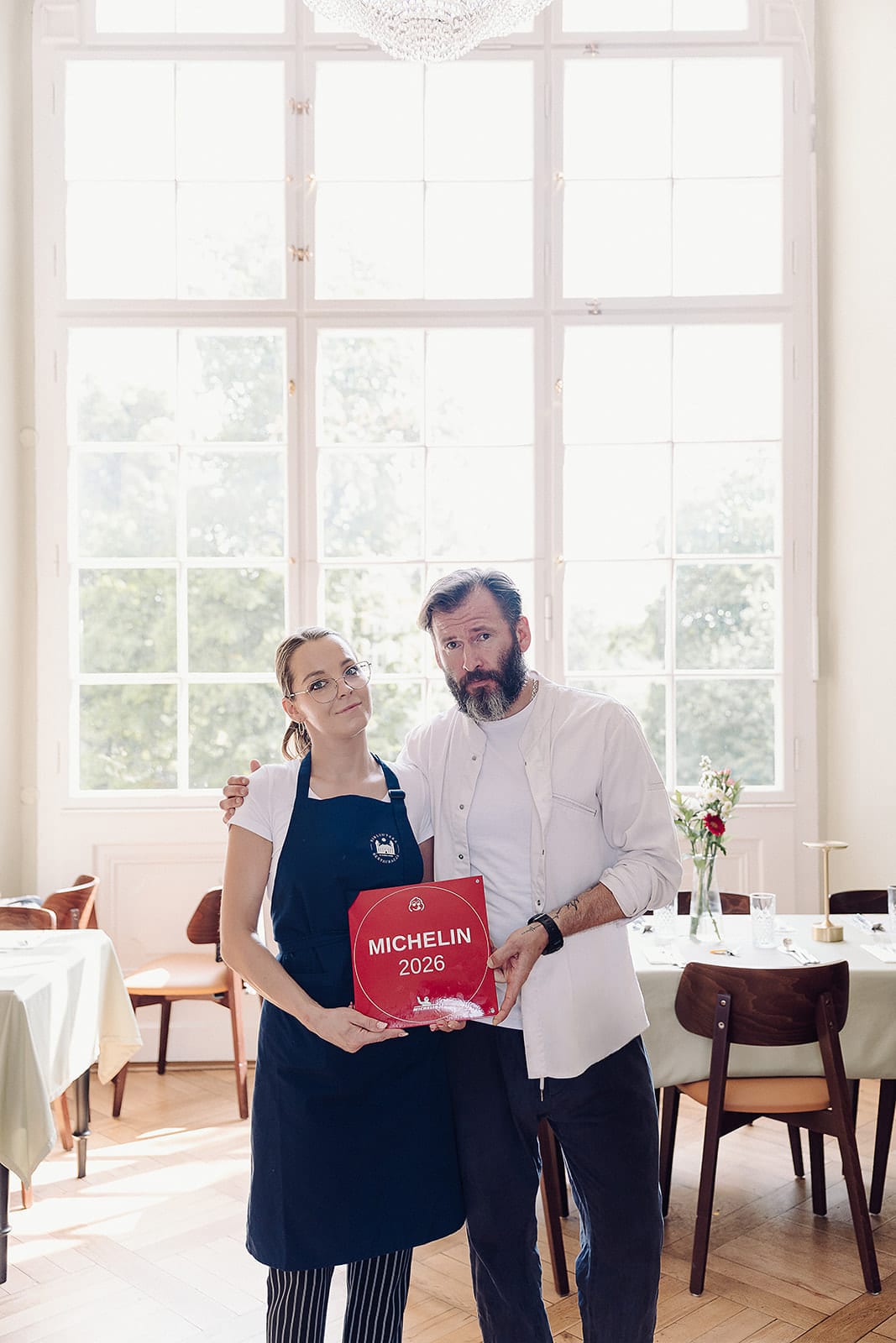 Dwie osoby z zespołu restauracji z tabliczką MICHELIN 2026 przy dużym oknie