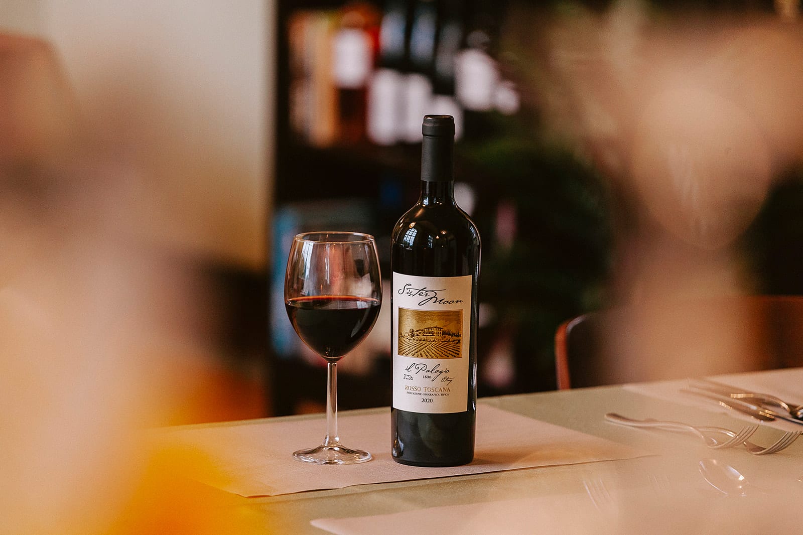 Eine Weinflasche mit Glas auf einem Tisch der Vinothek